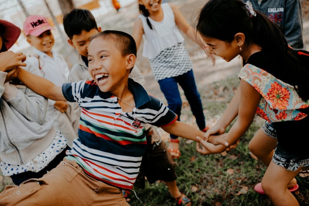 Children laughing and playing a cooperative outdoor group game.